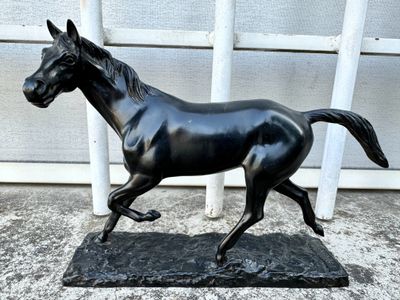 a statue of a horse running on a black base