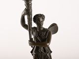 bronze statue of a woman holding a torch in her right hand