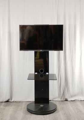 un téléviseur posé sur un meuble devant un rideau blanc