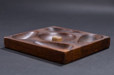 a small wooden plate with a gold ring on it