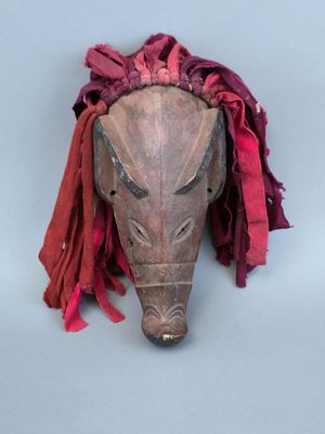 un vieux masque en bois avec un foulard rouge autour du cou