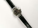 un gros plan d'une montre sur une surface blanche avec un fond blanc