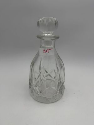une bouteille en verre à l'ancienne avec un bouchon, posée sur une surface blanche