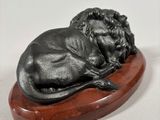 sculpture of a sleeping lion on a wooden base on a white background