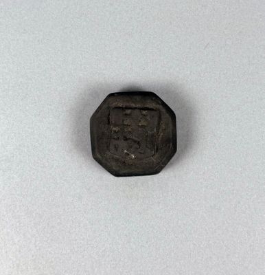 an old coin with a small face on it sitting on a white surface