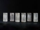 six clear glass vases are lined up on a black surface