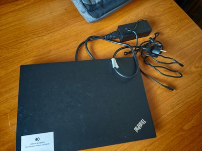 un ordinateur portable posé sur une table en bois, avec son chargeur