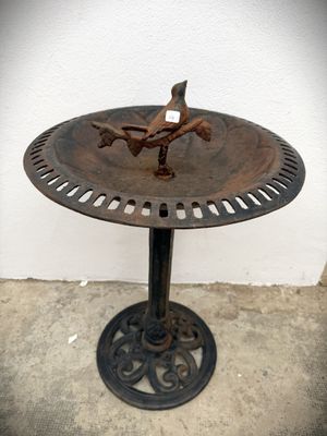 a bird sitting on top of a birdbath on a table