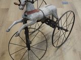 un cheval en peluche monté sur un tricycle posé sur un parquet