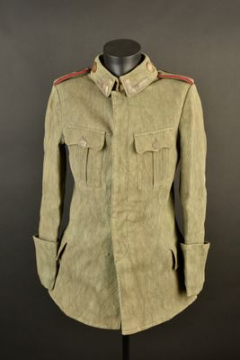 an old military coat on a mannequin stand against a black background