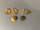 three gold metal buttons and a pair of earrings on top of a table