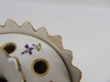 a close up of a white vase with purple flowers on it