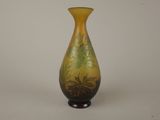 un vase jaune et vert posé sur une surface blanche