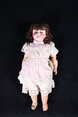 une poupée à l'ancienne, vêtue d'une robe blanche et aux cheveux bruns, sur fond noir