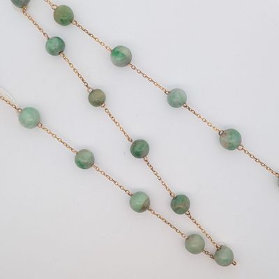 un gros plan d'un collier composé de perles vertes sur un fond blanc