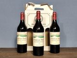 three bottles of red wine sit in front of a cardboard box