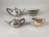 four pieces of silver tea and coffee set on a white surface