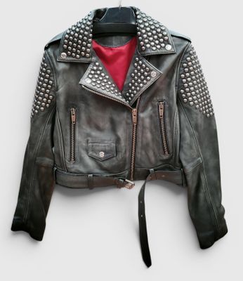 veste en cuir noir avec des clous sur les épaules et des fermetures éclair, suspendue à un cintre