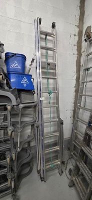 a room with a bunch of ladders and a blue bucket on the floor