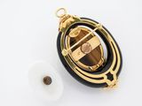 a close up of a gold and black broocher with a roll of tape