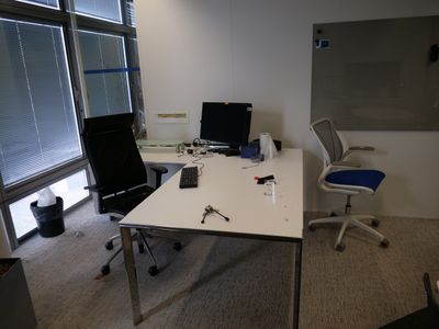 un bureau avec deux ordinateurs et une chaise dans un coin