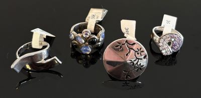 quatre types de bagues différents posés sur un fond noir, accompagnés d'une étiquette de prix