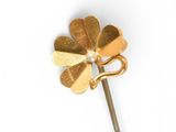 a gold flower on a stick with a pearl in the middle