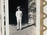 an old black and white photo of a sailor standing in front of a building