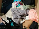 a cardboard box full of clothes and clothes on the floor