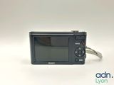 the camera is sitting on a white surface with a cord attached to it
