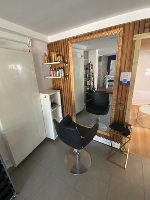 une photo d'un salon de coiffure avec un fauteuil et un réfrigérateur