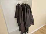 three coats hanging on a clothes rack in a room