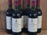 four bottles of wine are lined up on a wooden shelf