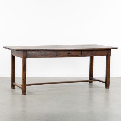 une table en bois avec un tiroir en dessous, posée sur un sol en béton