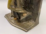 une statue en bronze d'un homme assis sur un rocher