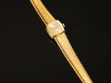 a gold watch on a black surface with a black background