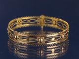 gros plan d'un bracelet en or sur une surface noire