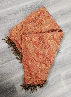 un gros plan sur une écharpe à motifs paisley orange posée sur un parquet