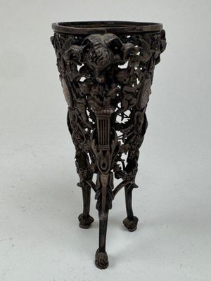 a black vase on a stand on a white surface