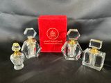 trois petits flacons de parfum en verre, présentés dans une boîte rouge posée sur un fond noir