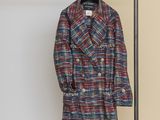 plaid coat hanging on a clothes rack in front of a white wall