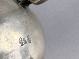 a silver tea pot with a handle on a table