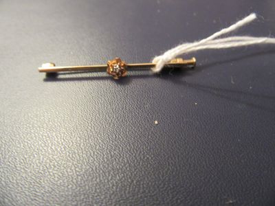 une broche en or ornée d'une fleur, posée sur un fond noir