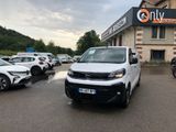 une camionnette blanche garée devant un immeuble devant lequel sont garées des voitures