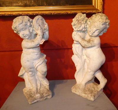 deux statues de chérubins posées sur une table devant un tableau