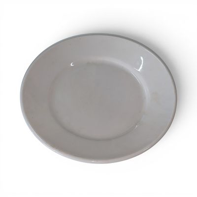 une assiette blanche posée sur une table blanche, avec une fourchette et un couteau