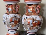 une paire de vases asiatiques posés sur une table, avec un mur en arrière-plan