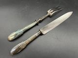 paire de couteaux anciens plaqués argent posés sur un fond noir