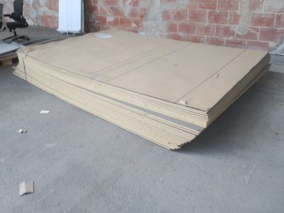 une pile de cartons posée par terre à côté d'un mur de briques