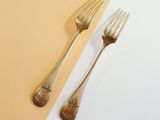 two forks and a spoon on a yellow and white table